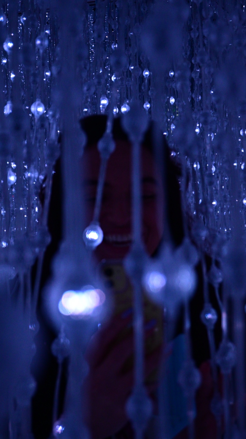 Child among blue hanging lights with a glowing phone